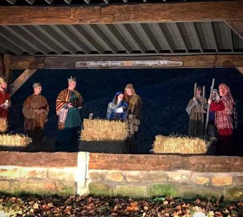 Nativity scene with figures depicting Mary, Joseph, and the Three Wise Men in a rustic setting with hay bales.