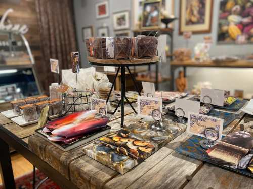 A cozy display of assorted chocolates and treats on a rustic wooden table in a charming shop.
