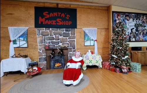 A festive scene featuring Santa's Makeshop, with a decorated tree, cozy fireplace, and holiday decorations.