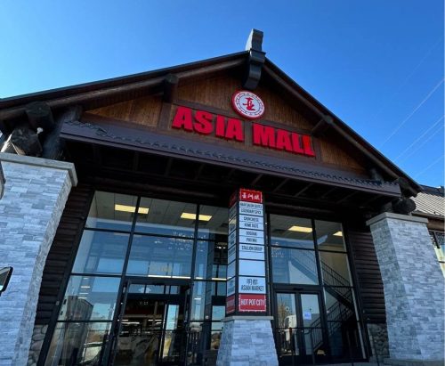 Exterior of Asia Mall featuring a wooden structure and large glass entrance under a clear blue sky.