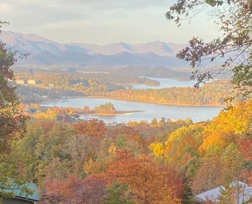 Scenic view of a lake surrounded by colorful autumn foliage and mountains in the background.