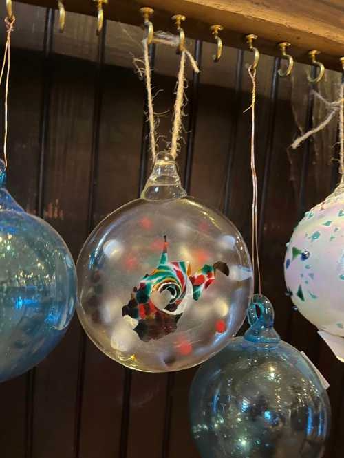 Colorful glass ornaments hanging on a display, featuring a swirl design in the center of one ornament.