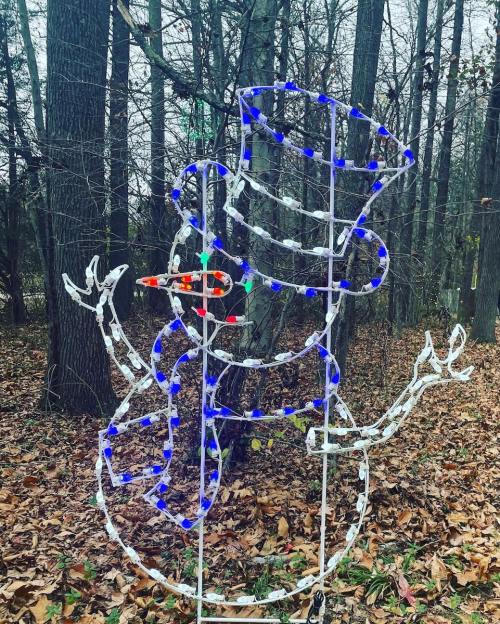 A light-up snowman decoration with a top hat, surrounded by autumn leaves and trees.