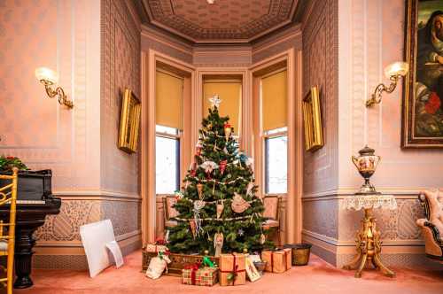 A beautifully decorated Christmas tree with gifts underneath, set in an elegant room with ornate walls and furnishings.