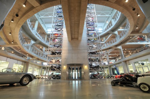 A modern car museum interior featuring multiple levels of vehicles displayed in a circular structure.