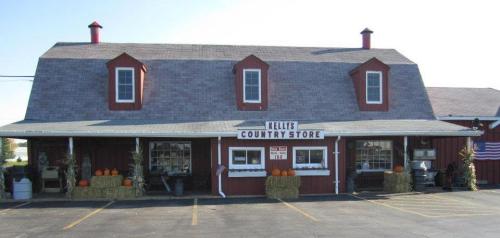 A red barn-style country store with a sloped roof, pumpkins outside, and hay bales in front.