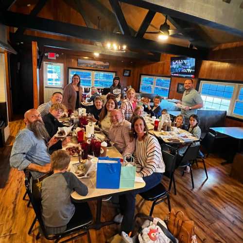 A large group of people gathered around a table in a cozy restaurant, enjoying a meal together.