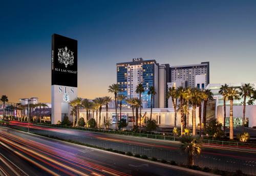 SLS Las Vegas hotel at dusk, featuring palm trees and a busy street with light trails.