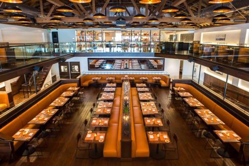 A spacious restaurant interior with wooden floors, orange booths, and tables set for dining under modern lighting.