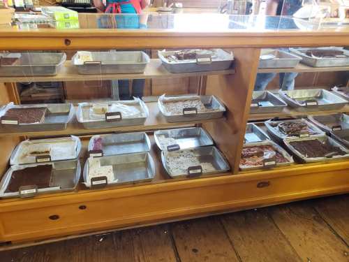 A wooden display case filled with various trays of desserts, including brownies and other treats.