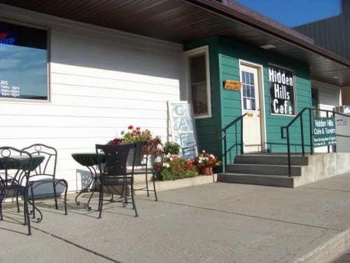 Exterior of Hidden Hills Café with a green and white facade, outdoor seating, and flower planters.