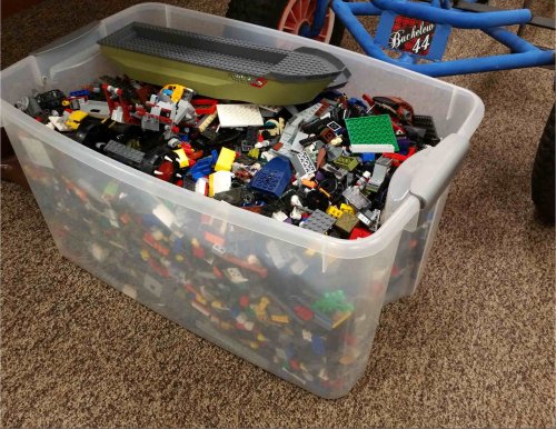 A clear plastic bin filled with a colorful assortment of LEGO bricks and pieces.