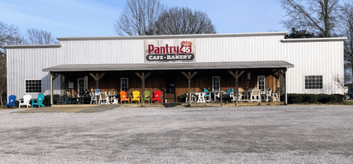 A rustic café-bakery with a sign reading "Pantry 45," featuring colorful chairs outside and a gravel parking area.