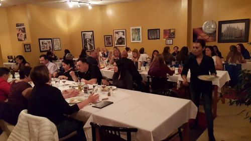A lively restaurant scene with diners at tables, enjoying food and drinks, and a server carrying a plate.