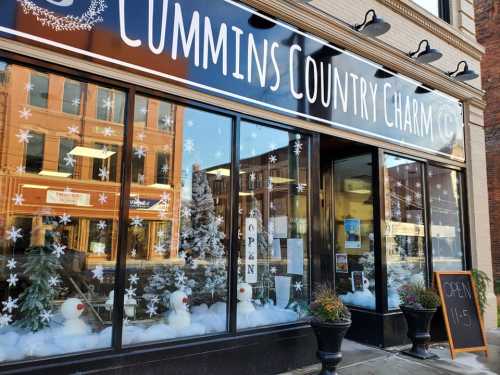 Storefront of Cummins Country Charm, decorated with snowflakes and winter decor, featuring a sign that says "OPEN."