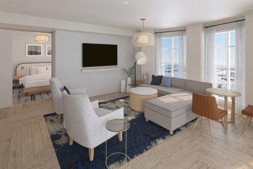 Modern hotel room featuring a cozy living area with a sofa, chairs, coffee table, and large windows with a view.