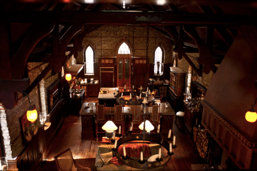 A cozy, rustic library with wooden beams, large windows, and warm lighting, featuring bookshelves and comfortable seating.