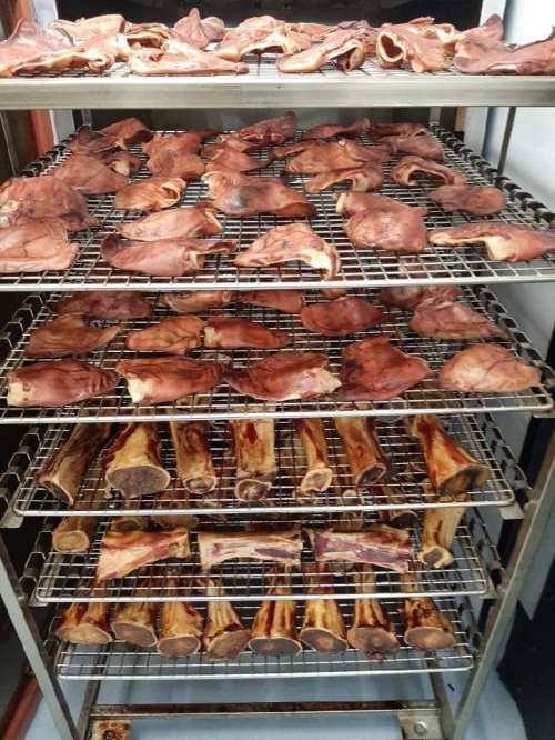 A metal rack filled with various types of smoked meats and bones, arranged in multiple layers.