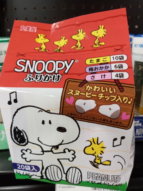A colorful box featuring Snoopy and Woodstock, labeled "Snoopy" with snacks inside, displaying playful graphics and text.
