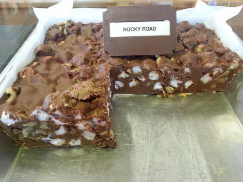 A tray of Rocky Road dessert, featuring chocolate, marshmallows, and nuts, with a label identifying it.