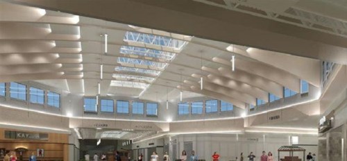 Bright, spacious interior of a modern building with high ceilings, large windows, and people walking around.