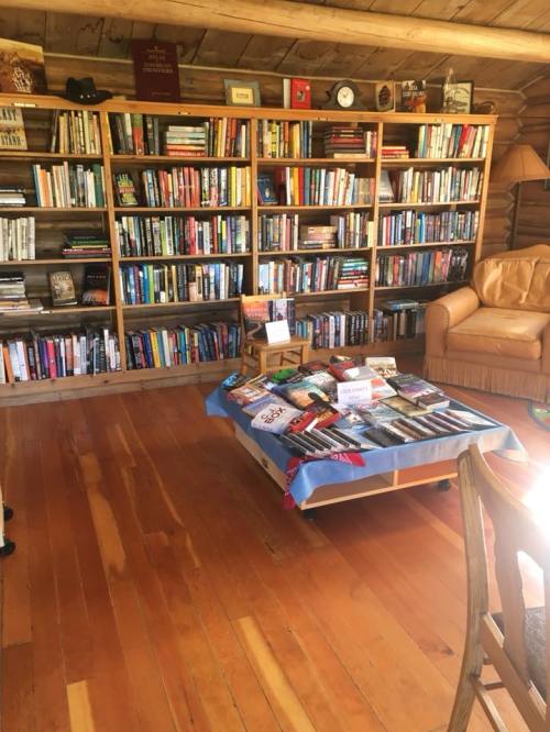 Cozy wooden room with bookshelves filled with books and a coffee table displaying various titles.