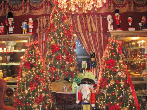 A festive room decorated with three Christmas trees, adorned with lights, ornaments, and nutcracker figures.