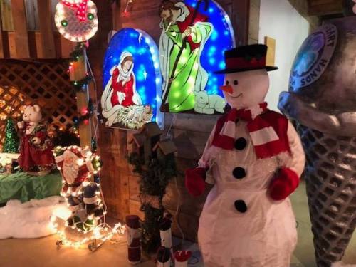 A festive display featuring a snowman, illuminated decorations, and holiday-themed figures in a cozy setting.