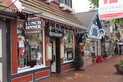 Charming street view of a festive restaurant in Solvang, decorated for the holidays with lights and Santa-themed decor.