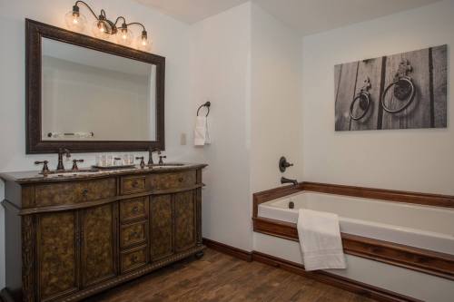 A stylish bathroom featuring a wooden vanity, large mirror, and a bathtub with a towel draped over it.