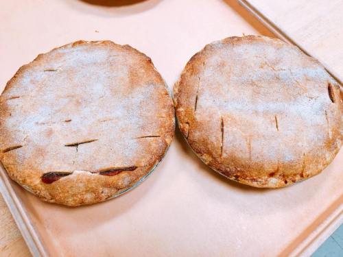 Two freshly baked pies with golden-brown crusts, lightly dusted with sugar, resting on a baking tray.