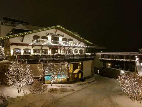 A cozy lodge adorned with festive lights, surrounded by snow-covered trees and a winter landscape at night.