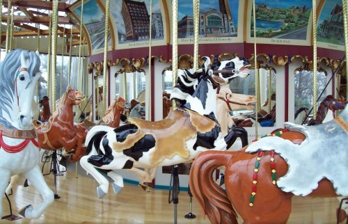 A colorful carousel featuring intricately painted horse figures in a vibrant indoor setting.