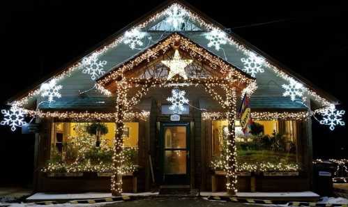 A cozy building adorned with bright holiday lights and snowflake decorations, glowing warmly at night.