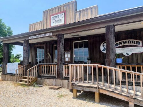 A rustic wooden store with a sign reading "Onward Store," featuring a porch and large windows.