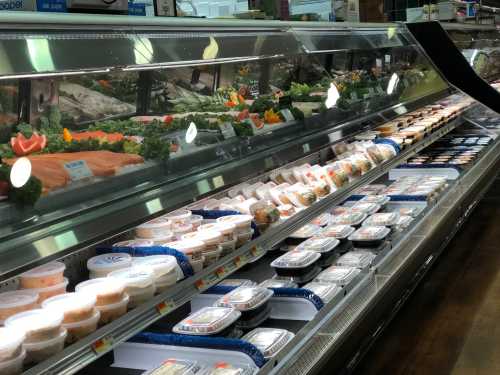 A refrigerated display case filled with various seafood, salads, and prepared meals in a grocery store.