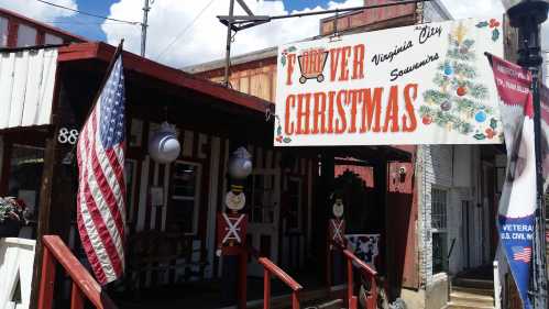 A festive storefront with a "Virginia City Souvenirs" sign, featuring Christmas decorations and a large American flag.