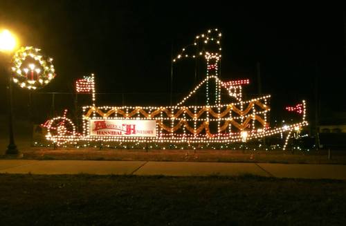 A brightly lit boat display decorated with festive lights, set against a dark night sky.