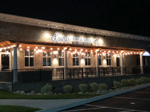 Exterior of Laura's Bar & Grill at night, featuring string lights and a welcoming sign.