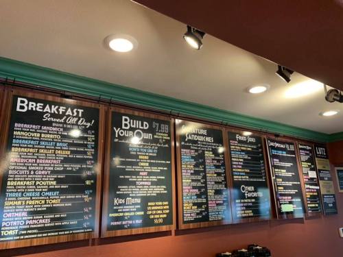 Menu board featuring breakfast items, sandwiches, and other favorites with prices listed. Brightly lit and colorful design.