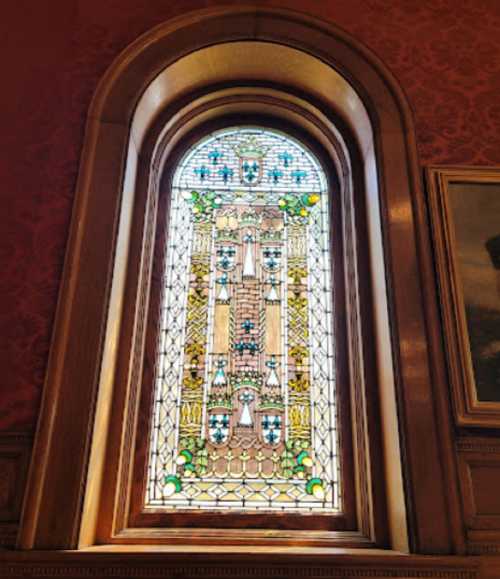 Stained glass window featuring intricate designs and vibrant colors, framed by wooden architecture.