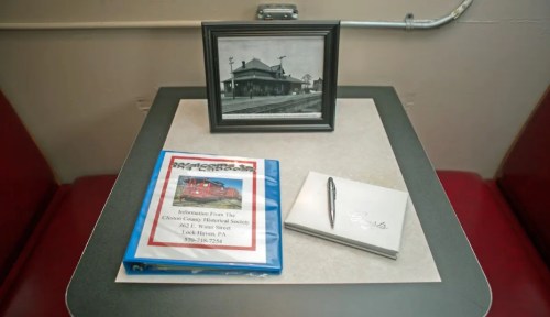 A table with a framed photo, a binder about a historical society, and a notepad with a pen.