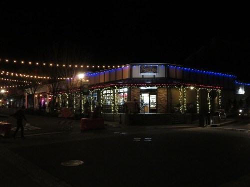 A brightly lit restaurant at night, adorned with colorful holiday lights and festive decorations.