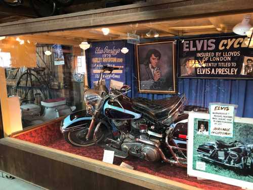 A vintage Harley-Davidson motorcycle displayed in a glass case, surrounded by Elvis memorabilia and photographs.