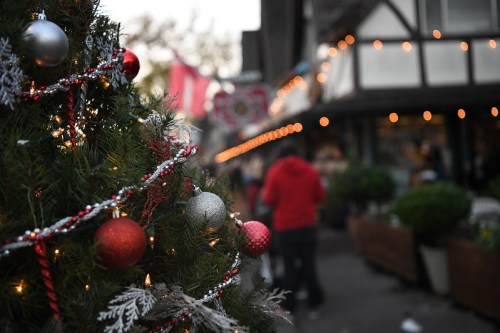 A decorated Christmas tree with ornaments and lights, with a festive street scene blurred in the background.