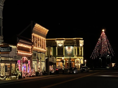 A charming street at night, adorned with festive lights and a large decorated Christmas tree.