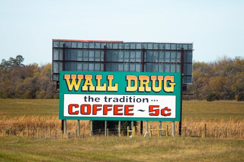 Sign for Wall Drug advertising 5-cent coffee, featuring bright colors and a rural backdrop.