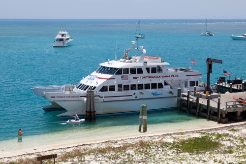 A large boat named "Yankee Freedom" docked at Dry Tortugas National Park, with clear blue water and other boats in the background.