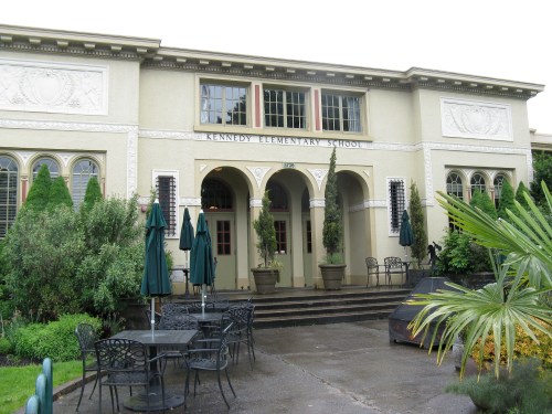 Exterior of Kennedy Elementary School featuring a decorative facade, entrance steps, and outdoor seating area.