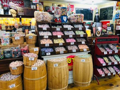 A colorful candy shop display with jars and barrels filled with various candies and sweets.
